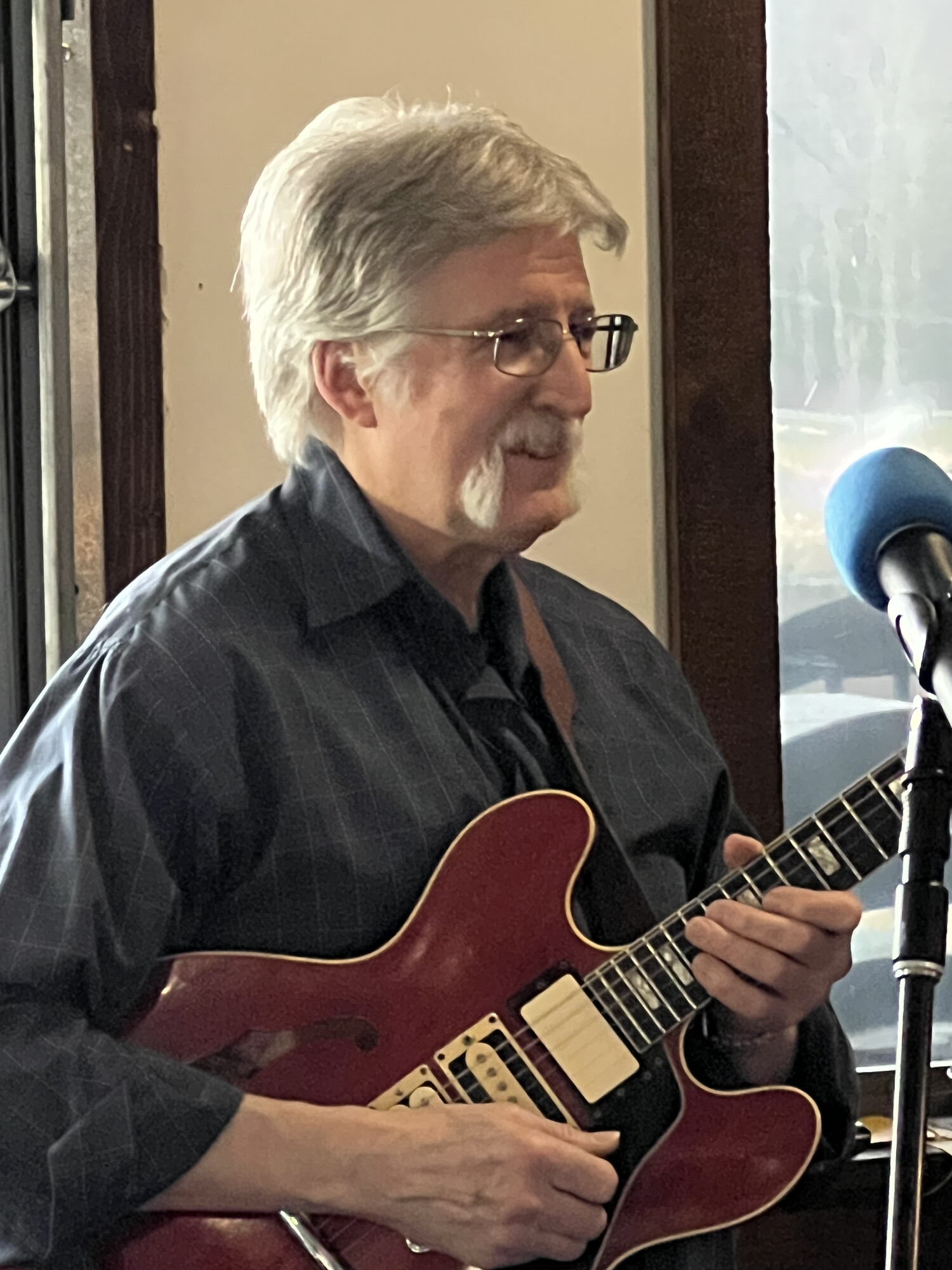 Charlie playing guitar by a sunlit window