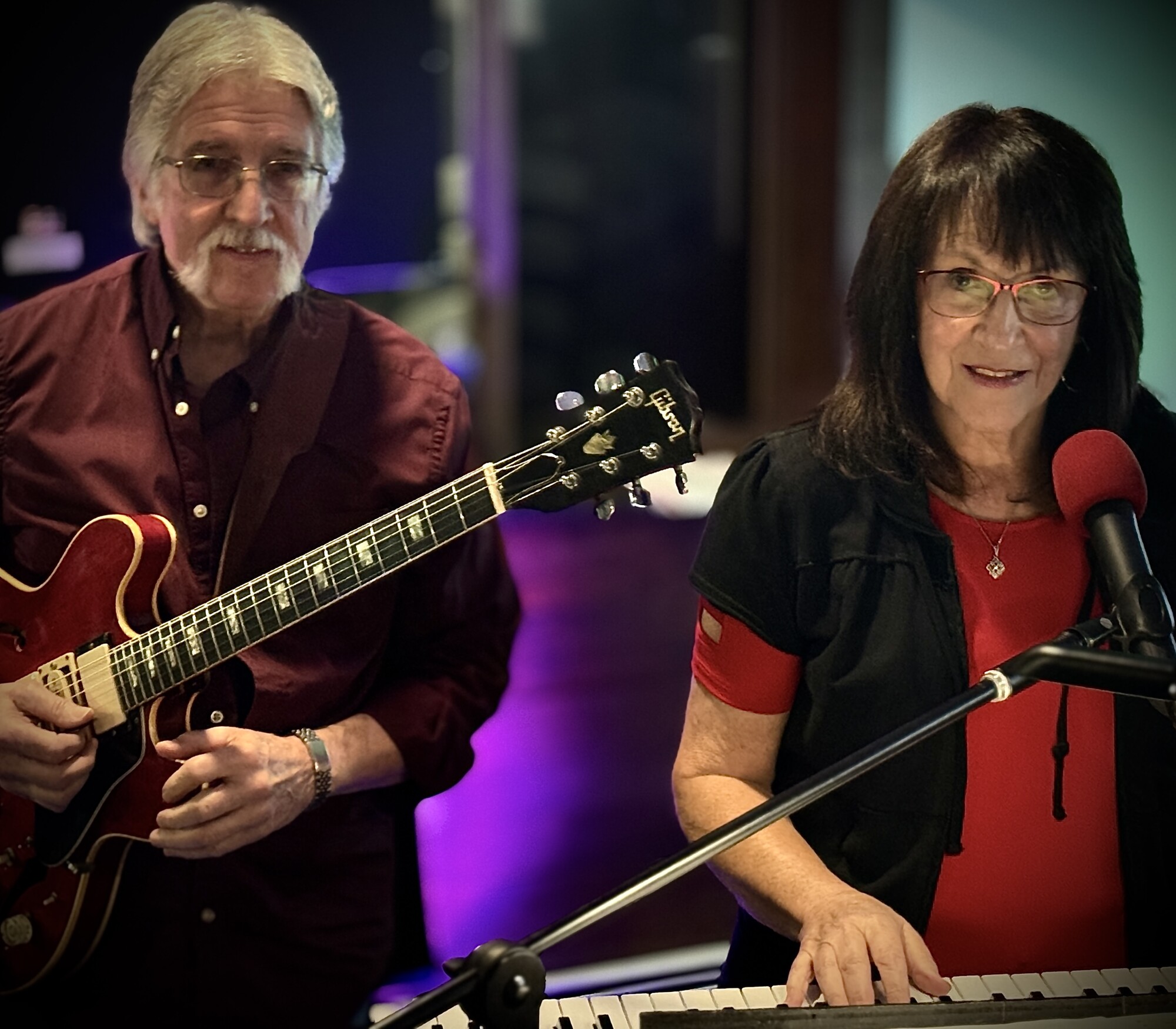 Charlie and Beverly close together at the keys and guitar in the studio