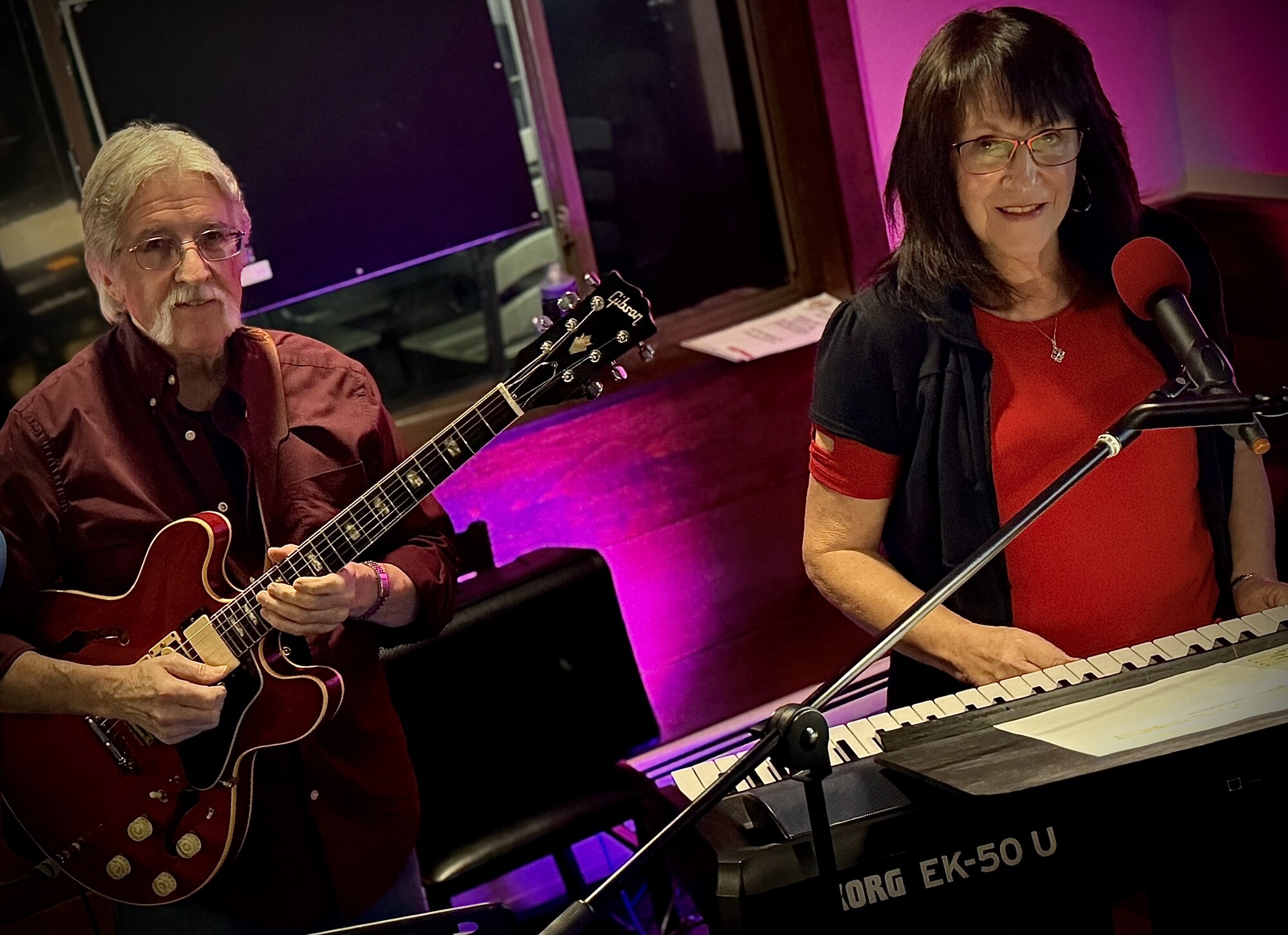 Charlie and Beverly performing in a studio lit with pink light